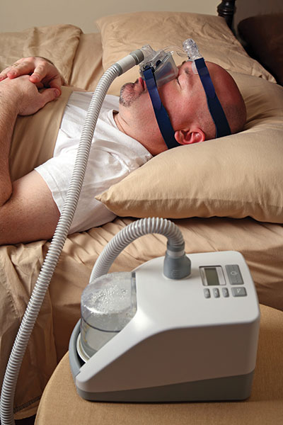 Man in bed wearing CPAP machine for sleep apnea