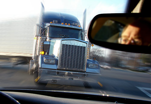 Semi truck turning corner and coming directly at passenger car