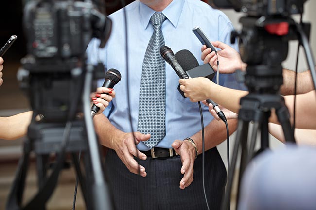 Man in a tie answering questions at a press conference