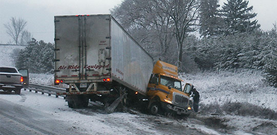 Truck jackknifed on the side of a snowy road