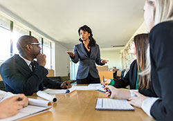 Woman speaking to a table of business people in a board room