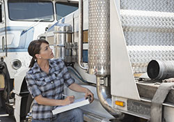 Woman holding a clip board inspecting a semi truck